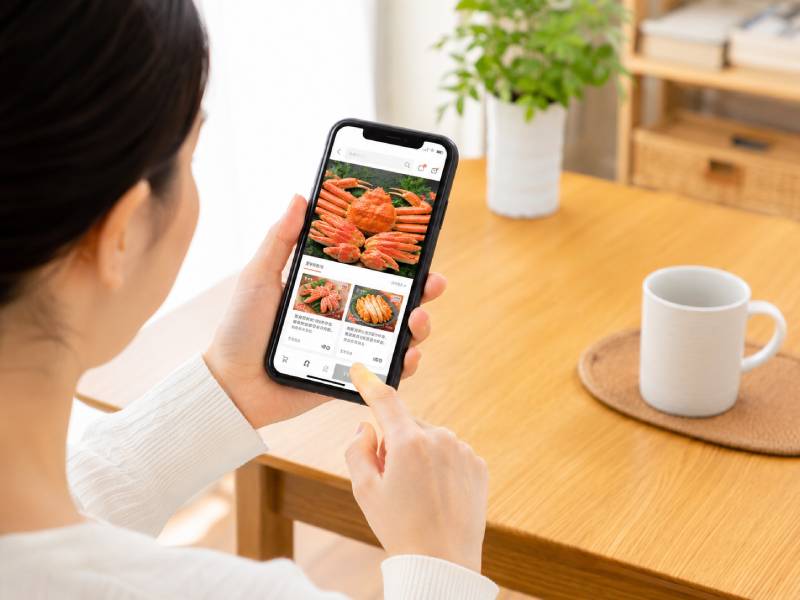 スマートフォンでカニ通販の商品内容を確認するイメージ